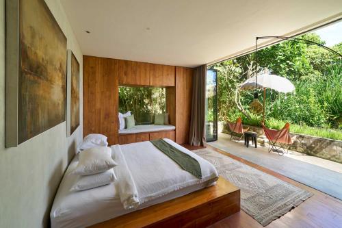 a bedroom with a bed and a large glass window at Chameleon Villa Bali in Tabanan