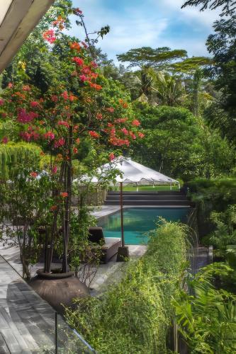 a garden with a swimming pool and flowers at Chameleon Villa Bali in Tabanan
