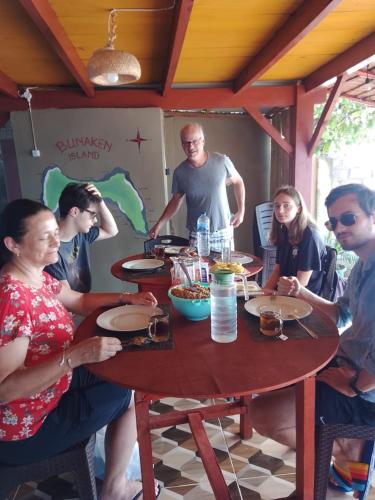 a group of people sitting around a wooden table at Three Ken Homestay & Cafe in Manado