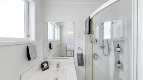 a white bathroom with a shower and a sink at Harbour View Motel and Waterfront Apartments in Tauranga