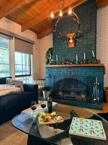 a living room with a fireplace and a table with wine glasses at Two Mountains Lodge - Modern Alpine Retreat with Spa - 3mins to Mt Buller in Mount Buller