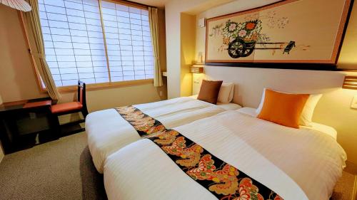 a bedroom with a large bed with white sheets and orange pillows at Kyoto Inn Gion in Kyoto
