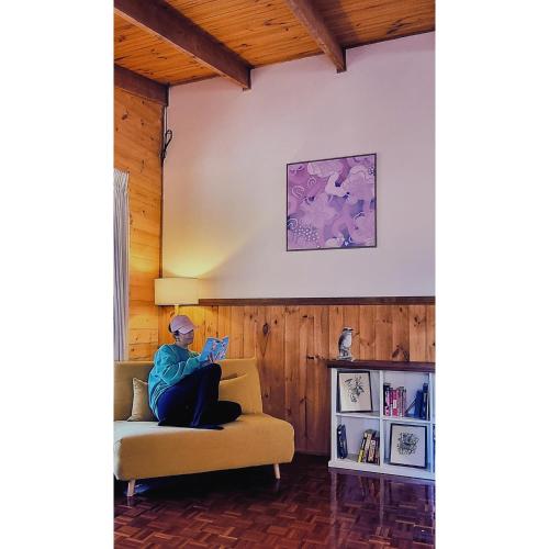 a woman sitting on a couch reading a book at Blue Wren Mews in Halls Gap
