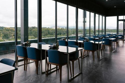 a row of tables and chairs in a room with windows at วัน บัดเจท เชียงราย บ้านใหม่ in Chiang Rai