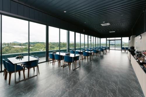 a dining room with tables and chairs and windows at วัน บัดเจท เชียงราย บ้านใหม่ in Chiang Rai
