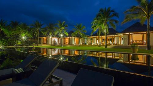 a villa with a swimming pool at night at Jivana Beach Villas in Natai Beach