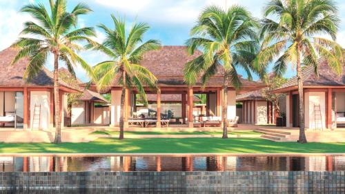 a house with palm trees in front of the water at Jivana Beach Villas in Natai Beach