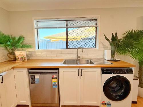 a kitchen with a sink and a washing machine at A Sunday Kind of Stay - 4 Bedroom 2 Bathroom Holiday Home Near Manly, Shops in Capalaba