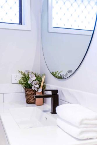 a bathroom with a mirror and a white sink at A Sunday Kind of Stay - 4 Bedroom 2 Bathroom Holiday Home Near Manly, Shops in Capalaba