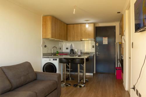 a living room with a couch and a kitchen at Nuevo Depto 3 camas, vista al estadio y estacionamiento gratis in Concepción