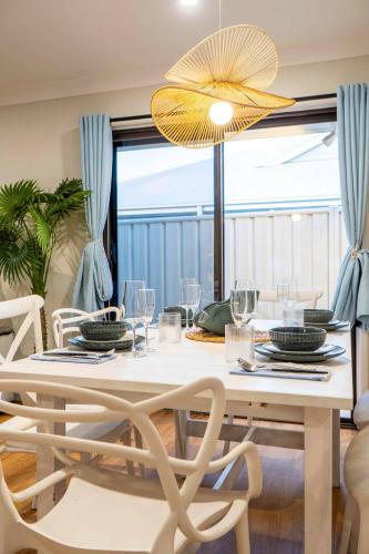 a dining room with a white table and chairs at A Sunday Kind of Stay - 4 Bedroom 2 Bathroom Holiday Home Near Manly, Shops in Capalaba