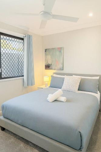 a bedroom with a large bed with a ceiling fan at A Sunday Kind of Stay - 4 Bedroom 2 Bathroom Holiday Home Near Manly, Shops in Capalaba