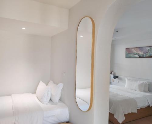 a white room with two beds and a mirror at Sky Garden Inn in Guilin