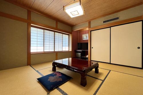 Habitación con mesa y puerta corredera grande en 湯の花ふわり 湯元館, en Hirayu