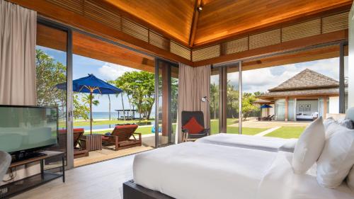 a bedroom with a bed and a tv and a patio at Jivana Beach Villas in Natai Beach