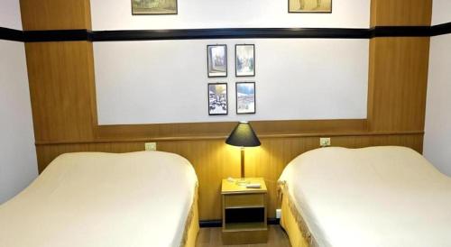 a room with two beds and a table with a lamp at Numsin Hotel in Ratchaburi