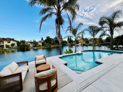 una piscina con dos sillas y una mesa en Experience Serenity Luxe 4BDR Lake House 25ft Pool, en Elk Grove