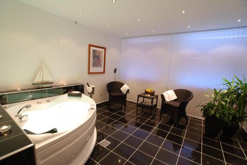 Hotel Pinenhus في Glyngøre: حمام كبير مع حوض استحمام و كرسيين