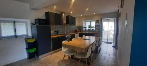 una cucina con un tavolo di legno e alcune sedie di Maison confortable 4 personnes - 2 chambres - Espaces partagés a Saint-Sauvant