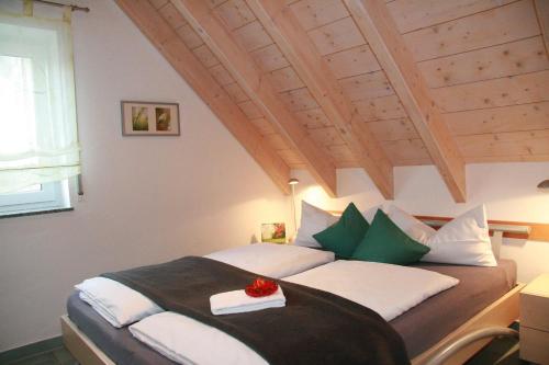 um quarto com uma cama com almofadas verdes e brancas em Ferienwohnungen Holder em Anhausen