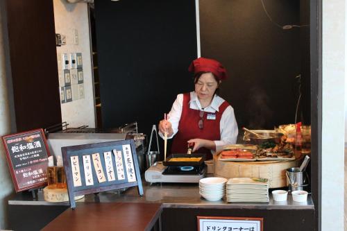 Una donna sta preparando il cibo in una cucina da ristorante di Shizunai Eclipse Hotel a Shinhidaka