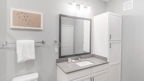 a white bathroom with a sink and a mirror at Landing at FarmHaus - Huntsville in Madison