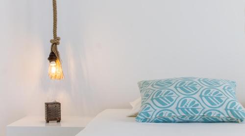 a pillow on a bed next to a lamp at Naxos Colosseo in Agios Prokopios