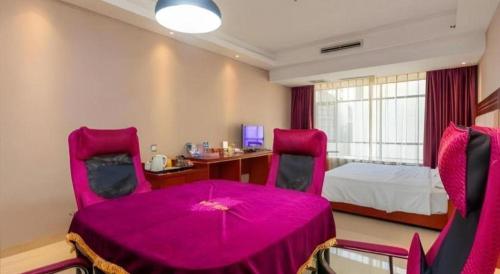a room with a pink table and chairs and a bed at Borrman Hotel Liuzhou High-Speed Railway Station in Liuzhou
