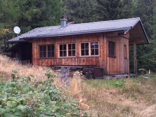 uma pequena casa de madeira numa colina num campo em Schalale em Kanzelhöhe