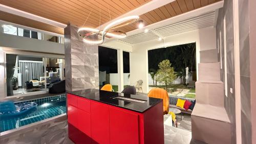 a kitchen and living room with a swimming pool and a red island at De Flourishing Hill Pool Villa , Cha Am in Ban Nong Chaeng