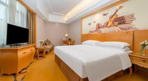 a bedroom with a large bed and a flat screen tv at Vienna Hotel Guangxi Fangcheng in Fangcheng
