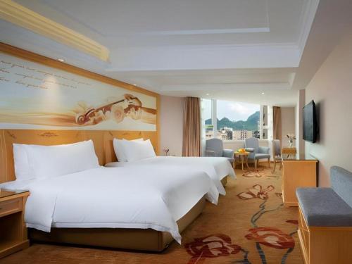 a hotel room with a large bed and a living room at Vienna Hotel Guangxi Hezhou Guposhan Suifeng in Hezhou