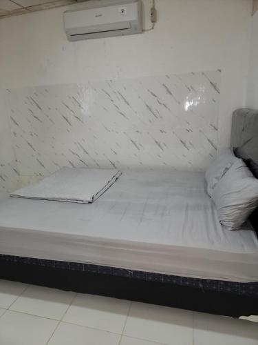 a bed with white sheets in a room at 88HappyHomestay in Luwuk