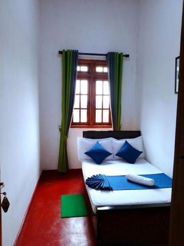 a bedroom with a bed with blue pillows and a window at Green Villa in Nuwara Eliya