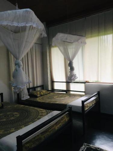two beds in a room with curtains and windows at Steps Kandy in Kandy