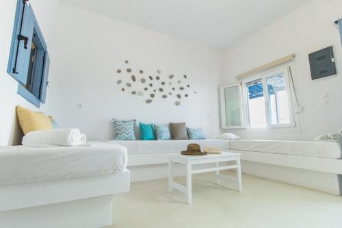 a white living room with two white couches and a table at Naxos Colosseo in Agios Prokopios