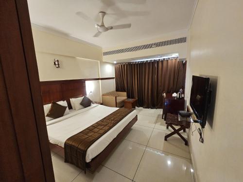 a hotel room with a bed and a television at Rain Drops Hotel in Chennai