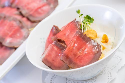 a bowl of food with meat and rice on a plate at Rizzan Sea Park Hotel Tancha Bay in Onna