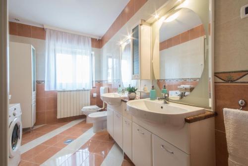 Un baño con dos lavabos, un inodoro y un espejo. en Villa Ritoša, a beautiful pool villa surrounded by greenery, en Trviž