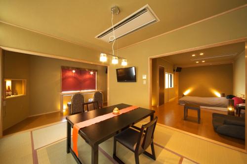a room with a dining table and a bedroom at Meitei no Yado Hotel Koshien in Fuefuki