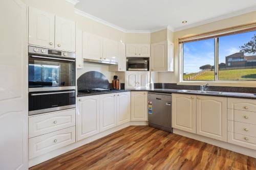 a kitchen with white cabinets and a large window at 4 BR house near beach sleeps 9 in Warrnambool