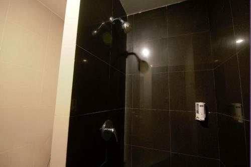 a bathroom with a shower with a black tile wall at Garuda Hotel Pontianak in Pontianak