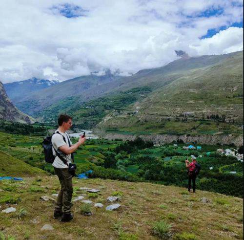 a man standing on a hill taking a picture of a valley at Rupi Rani Home Stay in Gushāl