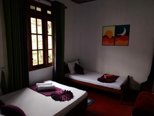 two beds in a room with two windows at Green Villa in Nuwara Eliya