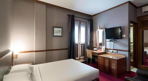 ein Schlafzimmer mit einem Bett, einem Schreibtisch und einem Fernseher in der Unterkunft Four Chain View Hotel in Singapur