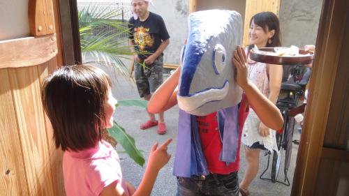 a group of children standing outside a door with a person wearing a mask at Katsuo Guest House in Kochi