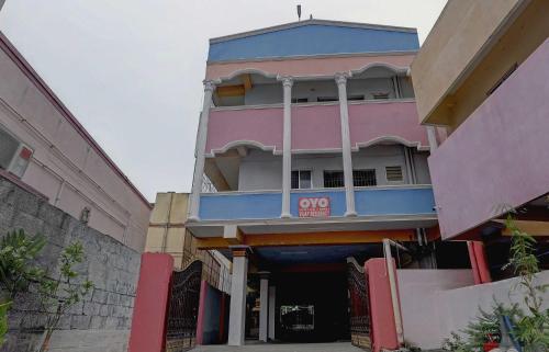 a pink and blue building with aoops sign on it at Super Collection O Velachery Railway Junction Formerly Vijay Guest House in Chennai