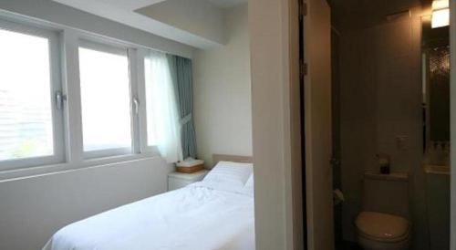um quarto com uma cama branca e uma janela em Wons Ville Myeongdong Hotel em Seul