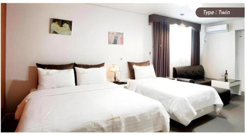 a hotel room with two beds and a chair at BENIKEA Technovalley Hotel in Daejeon