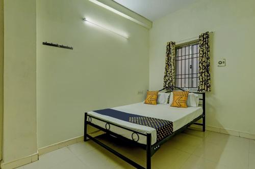 a small bed in a room with a window at Super Collection O Velachery Railway Junction Formerly Vijay Guest House in Chennai